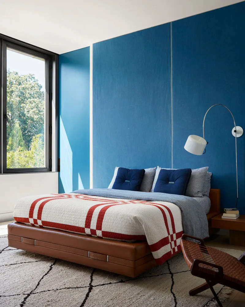 Modern Bedroom Design with Deep Blue Walls and Palm Leaf Pillows